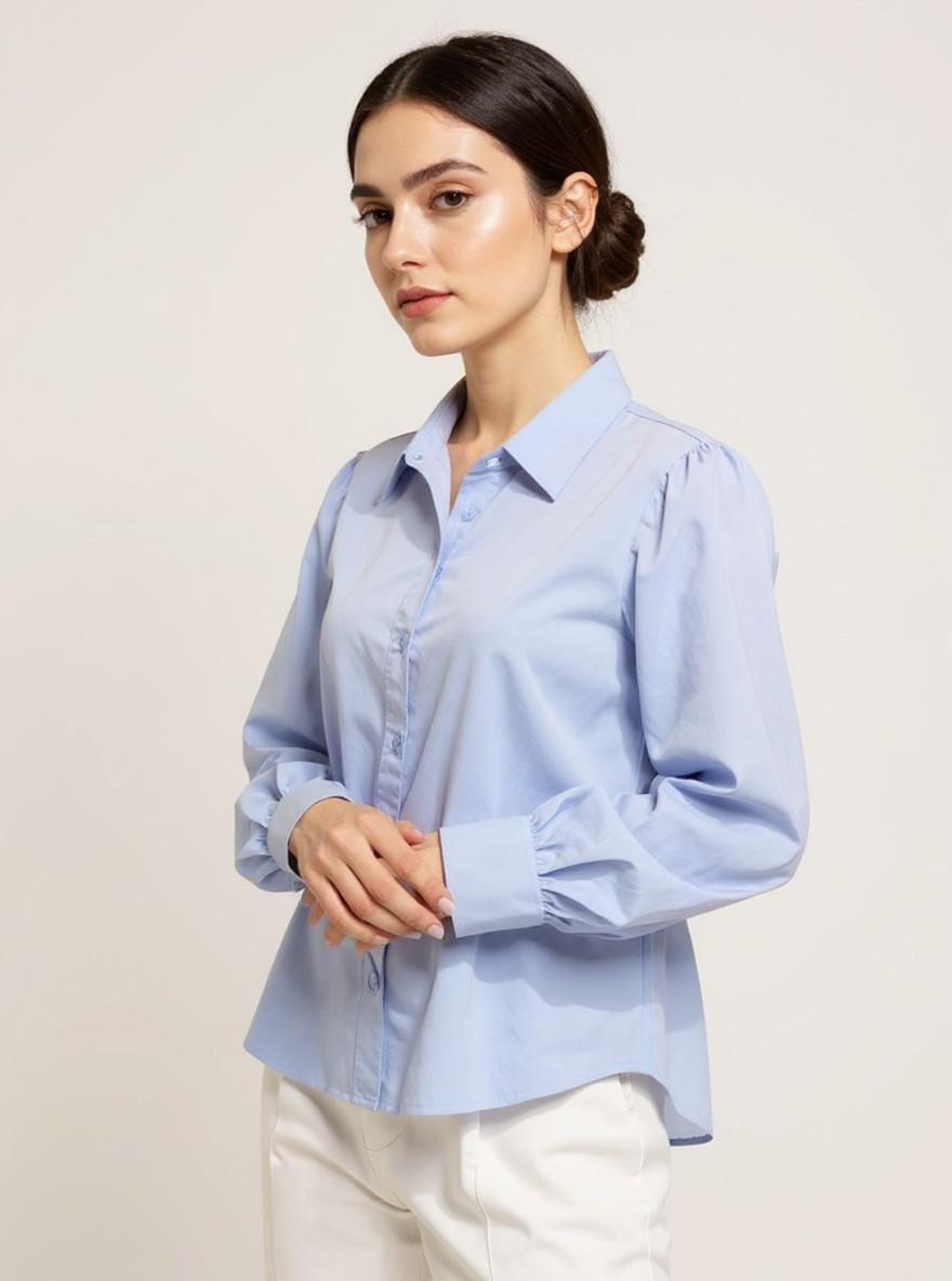 The Collar Shirt in Sky Blue, three-quarter side view with hands clasped, close-up of the gathered cuff