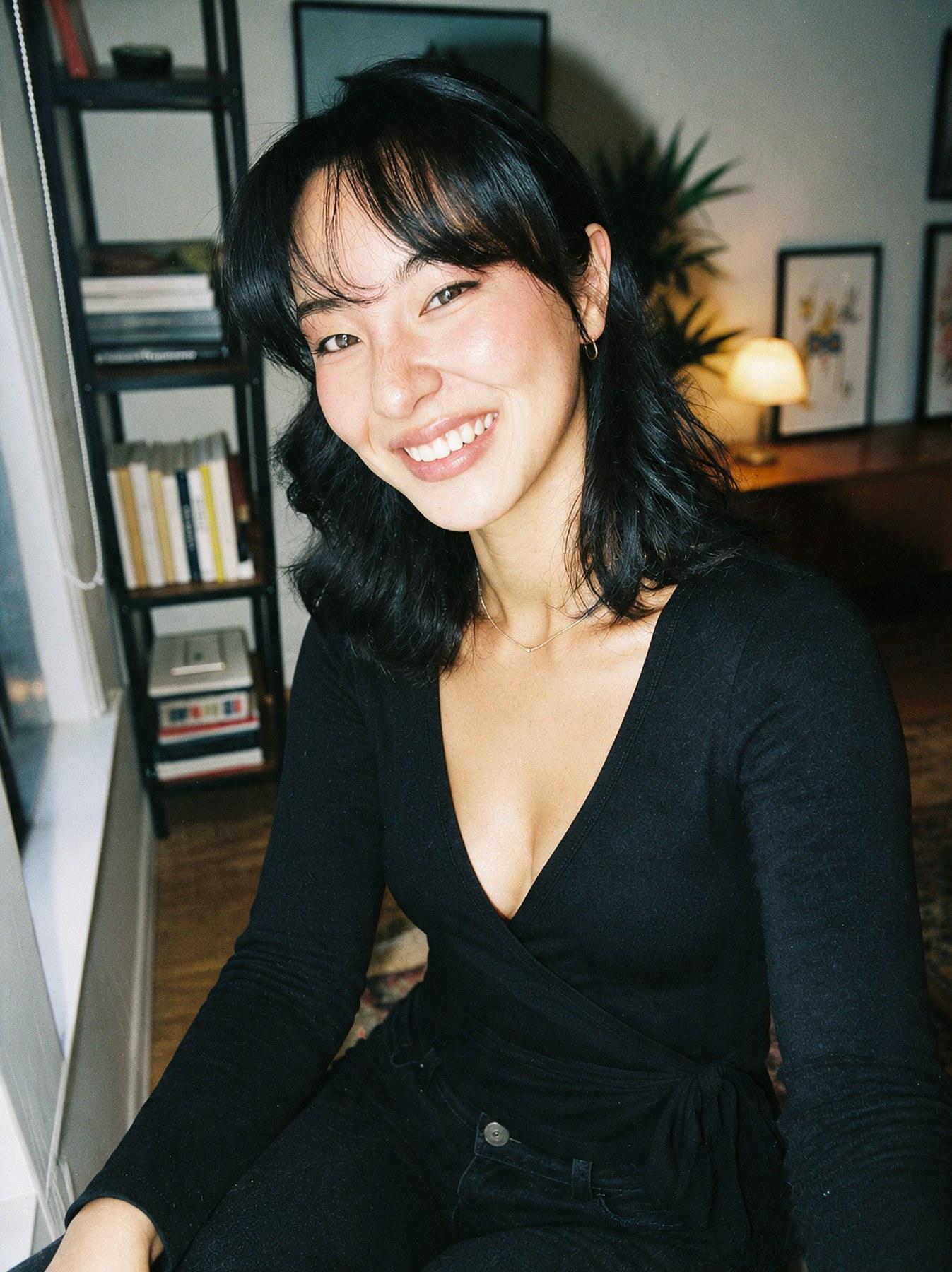 The Wrap Top in Black, close-up, seated and smiling
